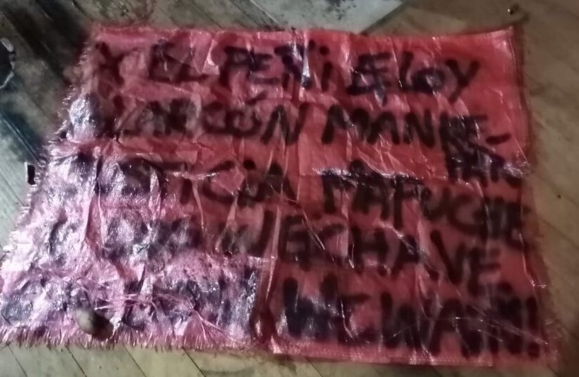 picture of a red canvas with the following text written in black: Por el peñi Eloy Elarcón Manquepán, Justicia Mapuche por los weychave caidos, ¡wewaiñ! 
