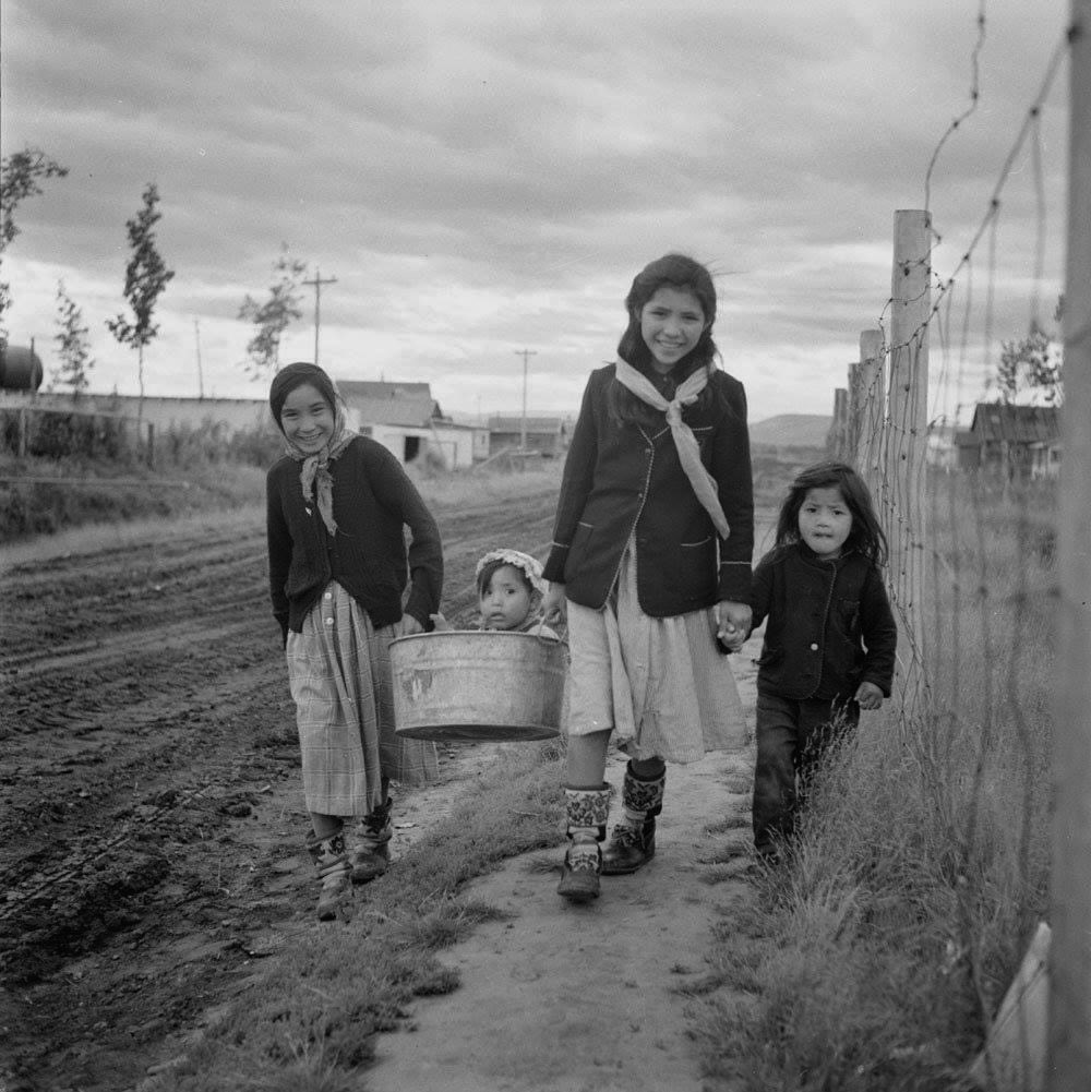 Alice Semple, 'Alfred' in tub and Ruth and Georgina Greenland (Gwich'in/Inuvialuit) in Aklavik, NWT 1956

Photo: Rosemary Gilliat / © Library and Archives Canada