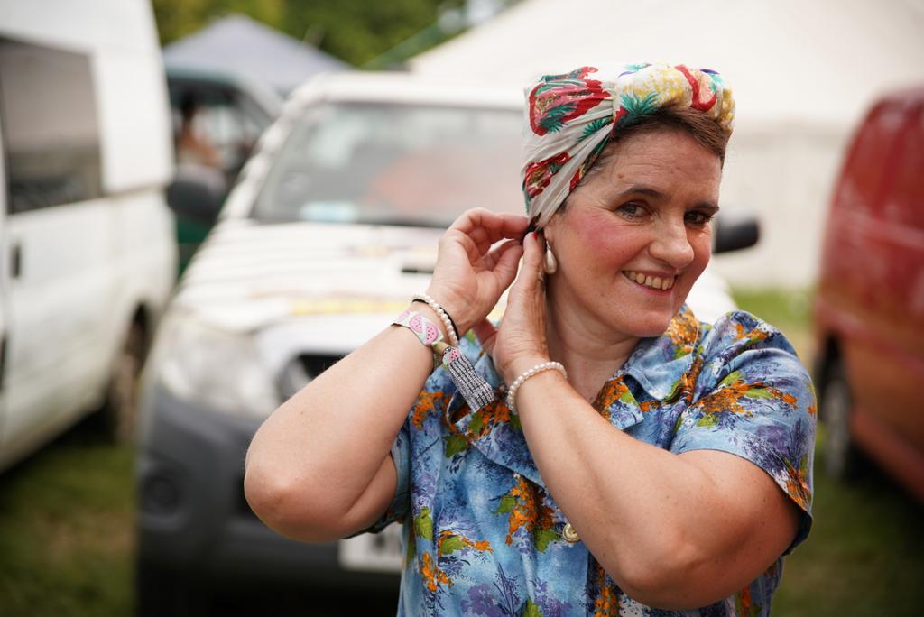 Gertie adds a finishing touch before heading out with the tea trolley into the fine fields of #GlastonburyFestival
#headscarf #couture #tealadiesontour 
#summerflorals 
<a href="/WalkaboutsTC/">Walkabouts Glastonbury T&C</a>