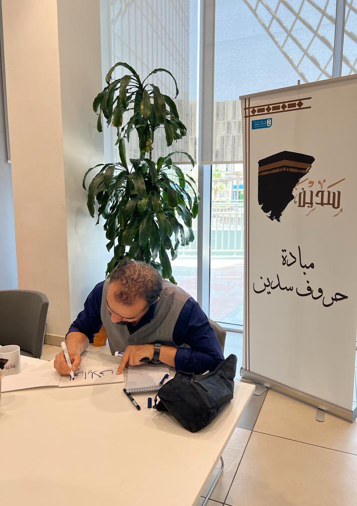 SadeenLetters's tweet photo. #مبادرة_سدين في @McitGovSa 

مشاركة الخطاط #أسامة في جناح مبادرة سدين، حيث قام بتعريف منسوبي الوزارة بنوع الخط المستخدم في كسوة الكعبة (خط الثلث) و الفرق بينه وبين بقية الخطوط العربية، كما تفاعل مع المشاركين بكتابة أسمائهم بخط الثلث https://t.co/PpZHIWAC5P