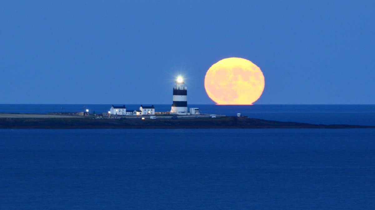 The strawberry full moon rising with Wexford's Hook Lighthouse.
Shot taken at Dunmore East Golf Course, Co Waterford. I've been planning this for 3 years and it finally came to fruition.
#strawberrymoon2022 
#strawberryfullmoon  
#StrawberryMoon #StormHour