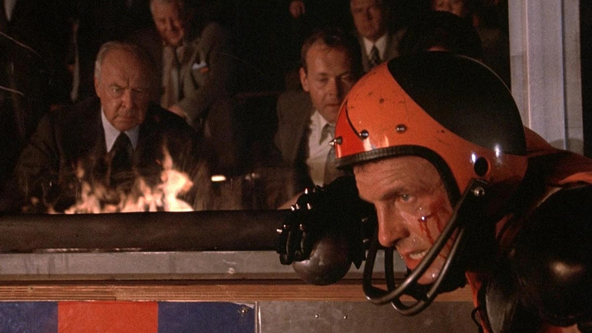 Rollerball (1975) takes place in a corporate dystopia where people live and often die over the ultimate combat sport. One superstar athlete struggles to make it to retirement with his dignity and neck intact.