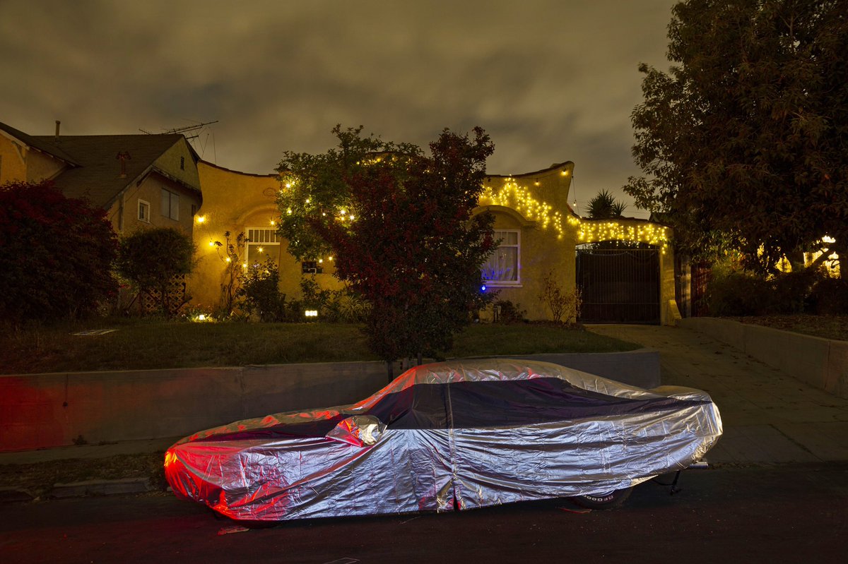 Illuminated by passing cars and brake lights, a car settles in for the night under her sleek and shiny cover in Eagle Rock, Los Angeles. 

#sleepingcars