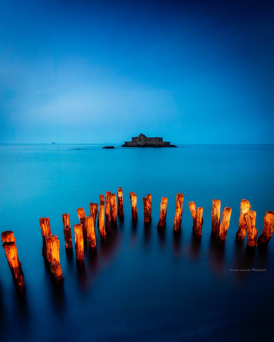 Juste avant la nuit à la lueur des lampadaires , les fameux brises lames qui protègent la ville de St Malo. Belle journée à tous.