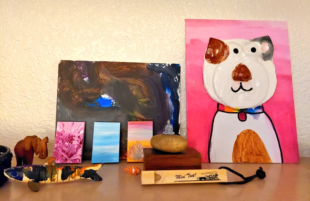 Boldtowngirl's tweet photo. How to display your art clutter in a fun way: I have my art (the 3 smalls), in front of my son's painting and wooden fish next to my daughter's Cat ceramic painting and some nicknacks. I've always loved this type of organized chaos. #artsy #clutter #momlife #artminded https://t.co/RotVS0epCx