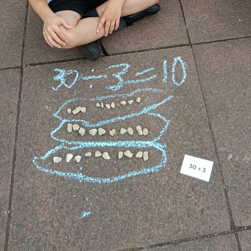 MissC_Whittle's tweet photo. We took division outside today, using some stones and chalk. The class practised using the array strategy to solve some division problems. I can see the 10kg bag of stones I've bought being useful for outdoor learning across the curricular areas! https://t.co/Lyi3lPbgpl