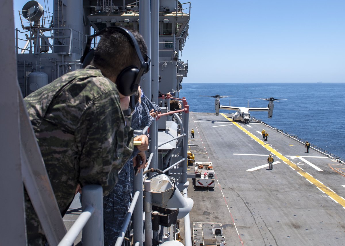 Embarked service members from the Republic of South Korea Navy and U.S. Navy Sailors observe a CMV-22 Osprey tilt-rotor aircraft, attached to Fleet Logistics Multi-Mission Squadron (VRM) 30, conduct flight operations with amphibious assault ship USS Essex (LHD 2), June 18, 2022.