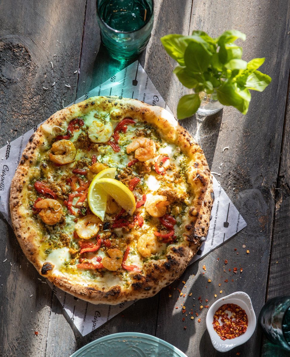 All you need is sunshine and fresh pizza! We've got you covered. This is our Shrimp &amp; Chorizo pizza with shrimp, chorizo sausage, cilantro pesto, roasted red peppers, fontina, gruyere, feta, and white cheddar.