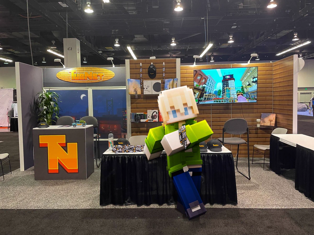 Tubbo's Minecraft Skin, holding TubNet lanyards, leaning against a TubNet Merch stall at VidCon