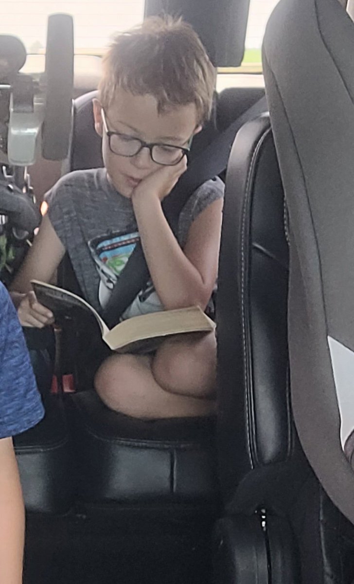 fischers5th's tweet photo. This kiddo is reading daily. Even when on the go. #JESReads Wyatt is borrowing a book from his Uncle and can't put it down. https://t.co/48XzGJ8cIQ