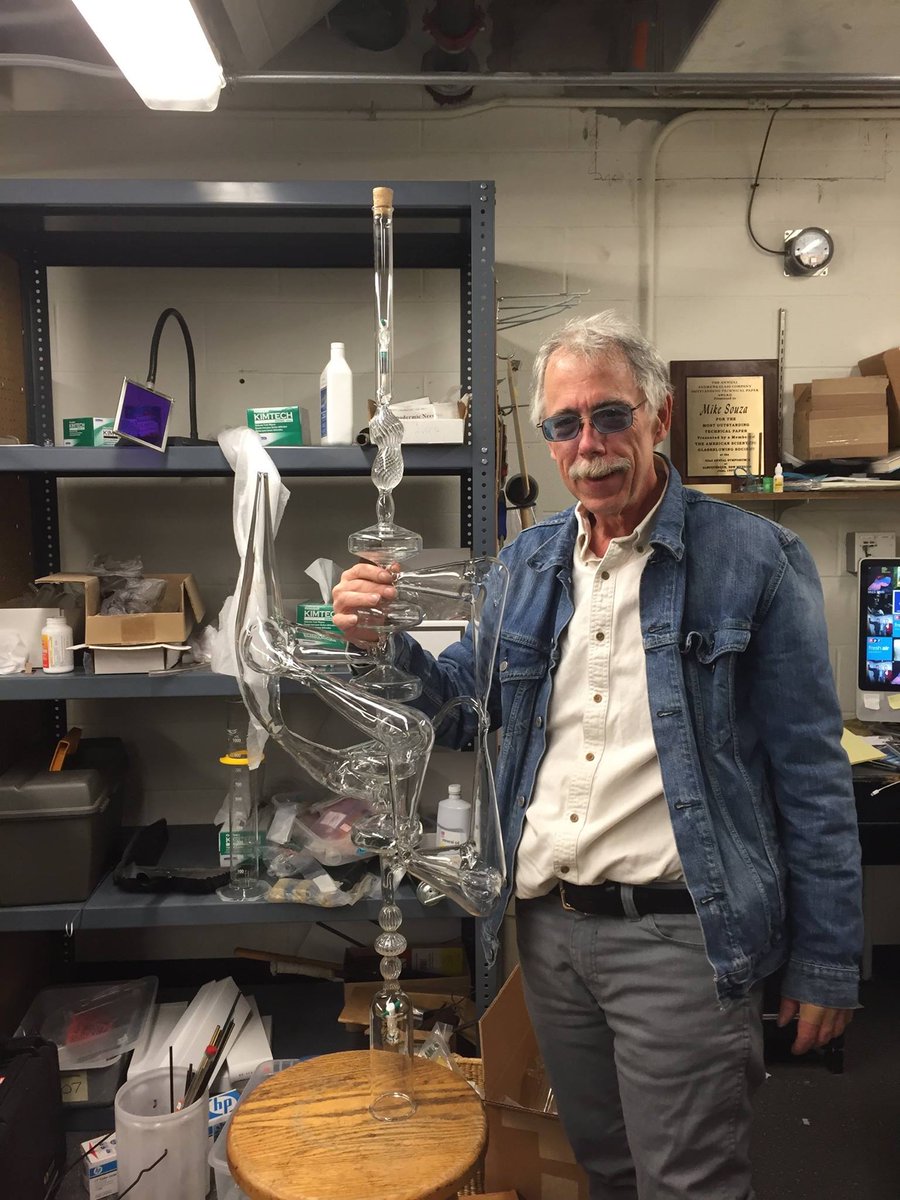 Color image of Mike Souza holding a glass project in his lab.