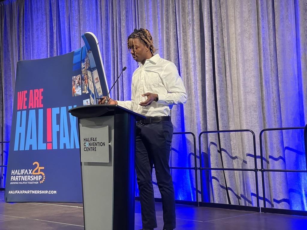 Kalade Kolawole-Boboye, <a href="/hopebloomshfx/">HopeBlooms</a> ‘s Lead Social Innovation Coordinator, is now on stage to share how Hope Blooms Market Dollars digital currency will create an equitable marketplace for all community members to shop.