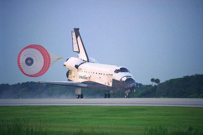 With its drag chute deployed, the Space Shuttle Columbia touches down on Runway 33 at Kennedy Space Center.