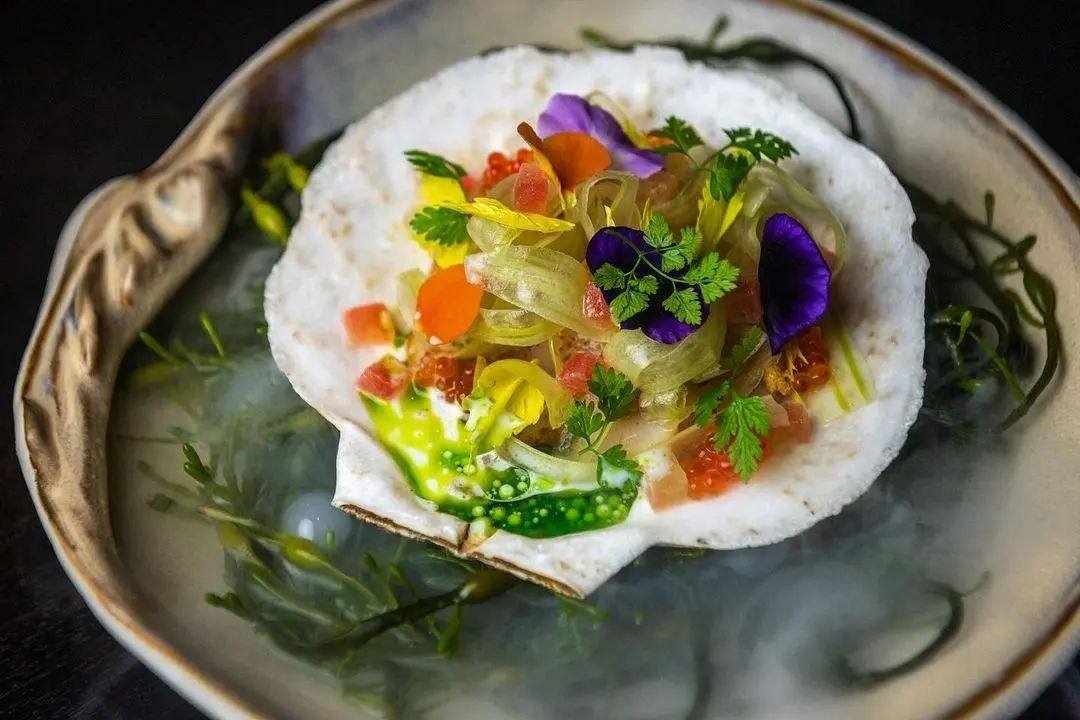 It's shellception over here-- a live scallop on the shell IN a Shell Plate from Studio Raw with espelette, trout roe, hidden rose apple, celery, lemon balm, and herb oil. 
📷: <a href="/Modena_DC/">Modena</a>