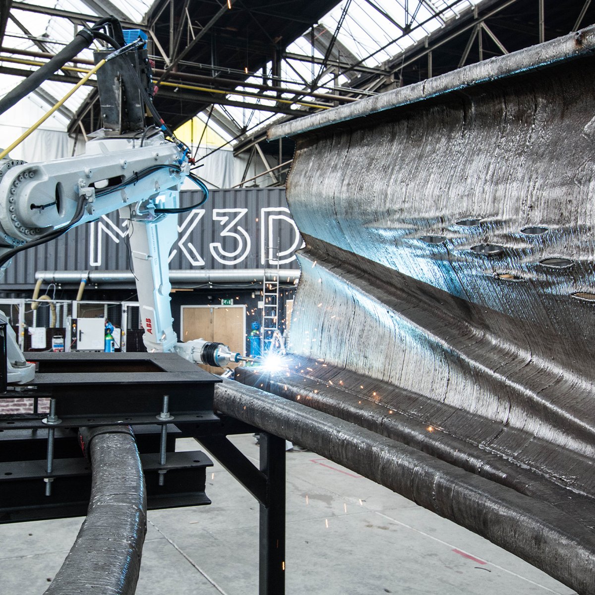 Arup's tweet photo. As the world’s first #3DPrinted steel bridge, the design of MX3D Bridge in Amsterdam sat outside standard design codes – so we created a rigorous testing regime to support the design and prove the structural capacity of the stainless steel #bridge. https://t.co/E7PqIzUpW1 https://t.co/2WlGfYVVDm