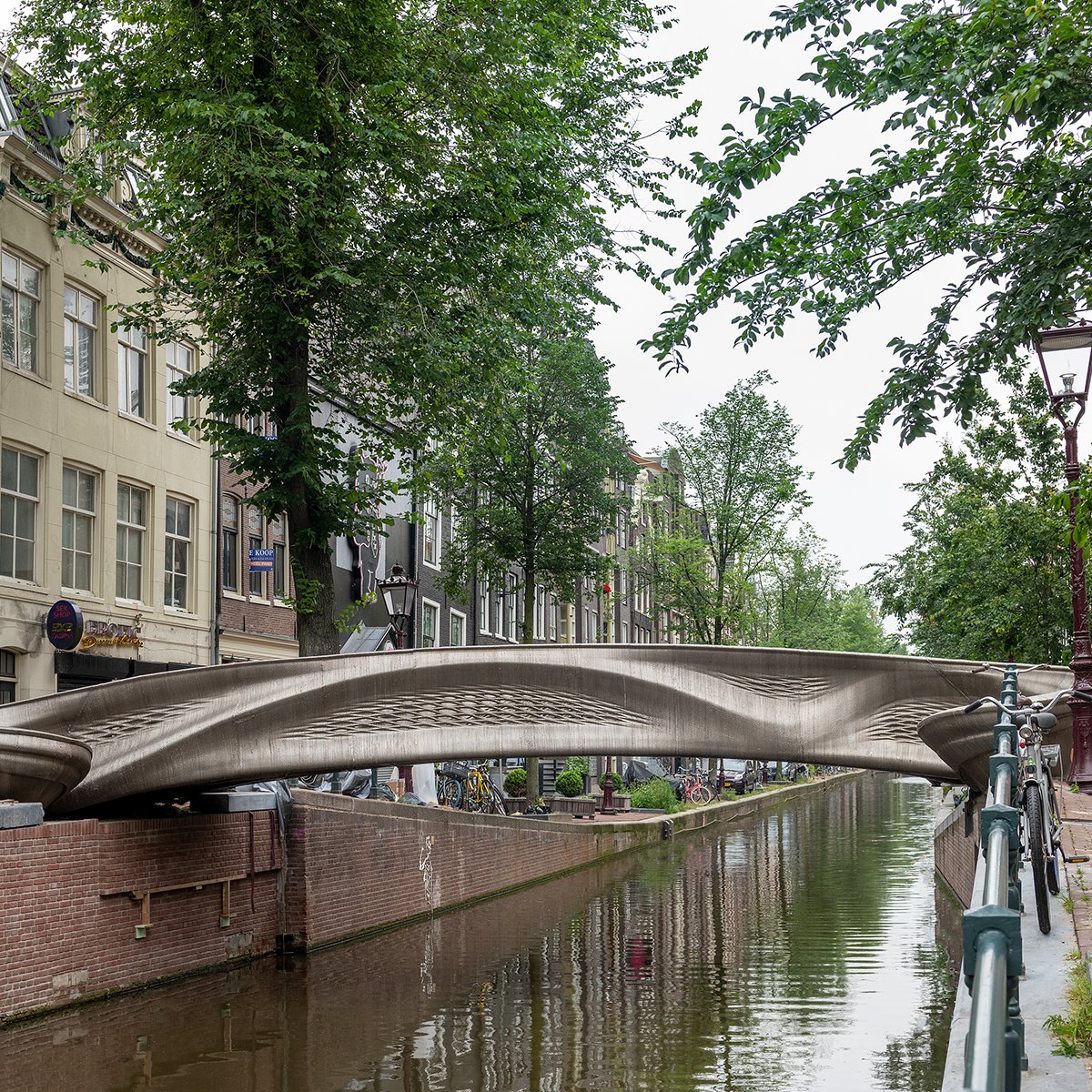 Arup's tweet photo. As the world’s first #3DPrinted steel bridge, the design of MX3D Bridge in Amsterdam sat outside standard design codes – so we created a rigorous testing regime to support the design and prove the structural capacity of the stainless steel #bridge. https://t.co/E7PqIzUpW1 https://t.co/2WlGfYVVDm