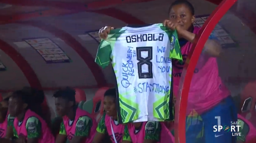 Foetbal247TBG's tweet photo. Tochukwu Oluehi holds up a shirt with a message for the injured Asisat Oshoala #WAFCON2022 #TotalEnergiesWAFCON2022 #NGABDI https://t.co/IQnT2IKgS8
