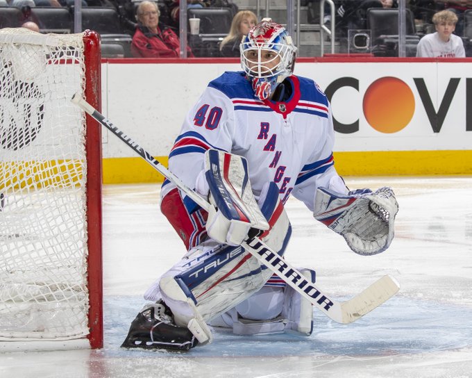 Alexandar Georgiev wearing a New York Rangers jersey standing in net prepared to block a shot on goal. 