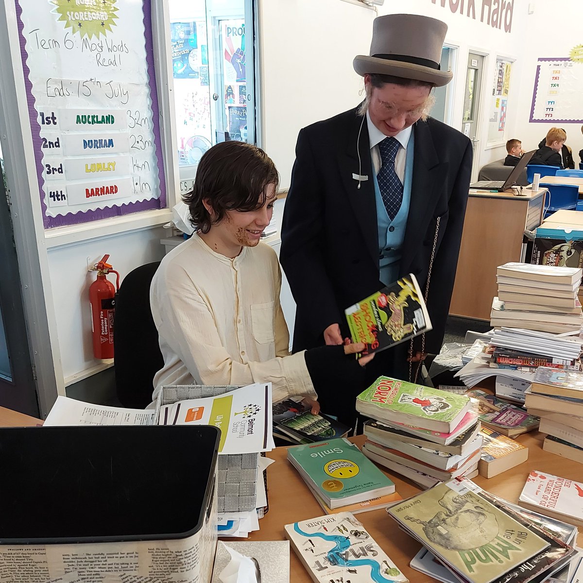 BCS_LRC's tweet photo. It's show week over in @BCS_Performing and our student librarians are multi-tasking between rehearsals! Thank you Bill and Mr Brownlow, an unlikely duo 🎭 Belmont's summer production of Oliver debuts this evening (13th) at 7pm https://t.co/5qiX6kWFj5