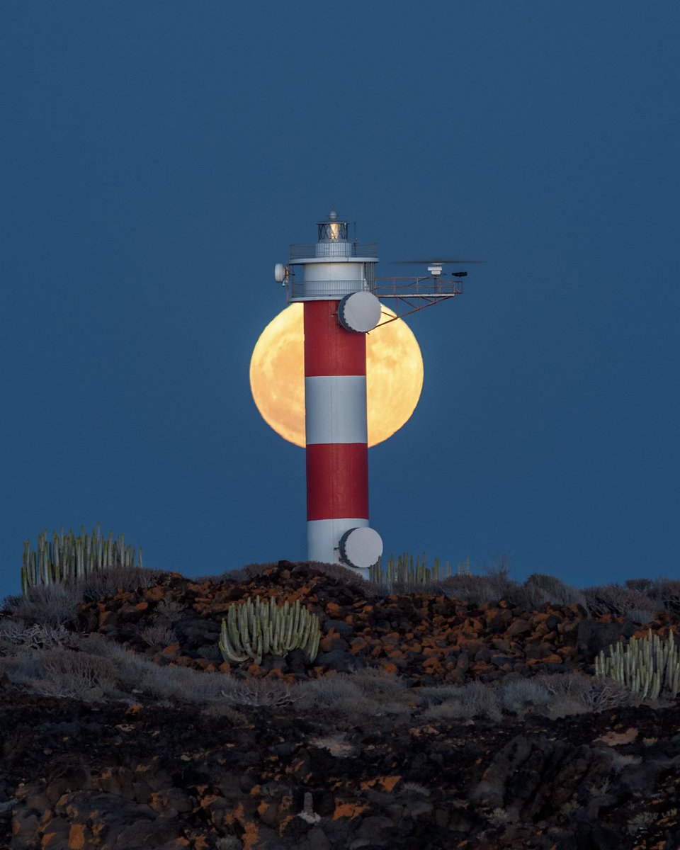 La última superluna del año sorprende saliendo detrás del faro de Punta de Rasca.