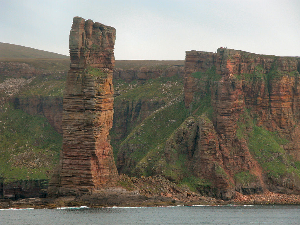 UndisScot's tweet photo. The towering Old Man of Hoy, with people on the cliff adding scale. The Old Man is barely part of Hoy, the second largest of Orkney’s islands at about 10 by 5 miles. Hoy’s name fittingly comes from the Old Norse for 'High Island'. More pics and info: https://t.co/X1ckdnxp6b https://t.co/r8XNyDTdcJ