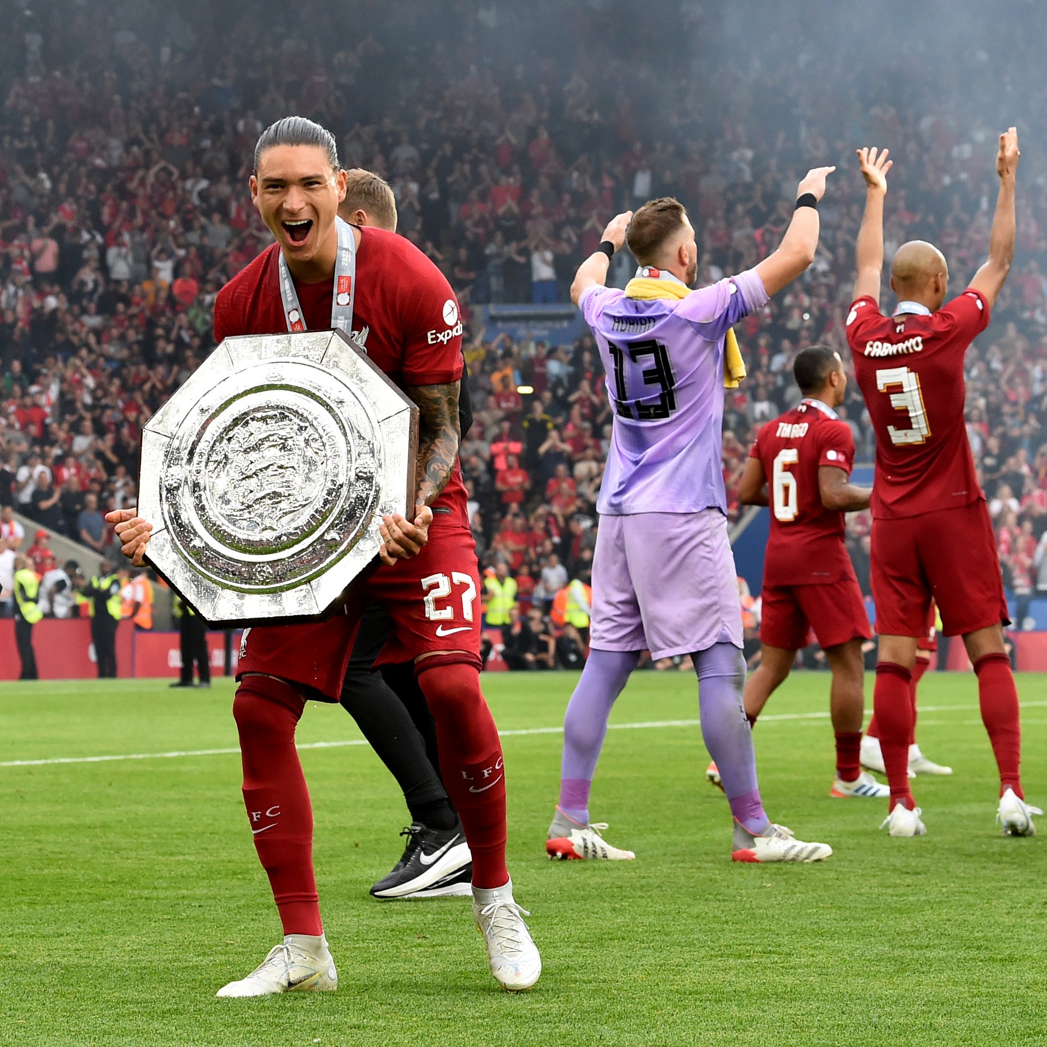 Darwin Nunez smiling with the Community Shield, with Adrian and Fabinho celebrating in the background.