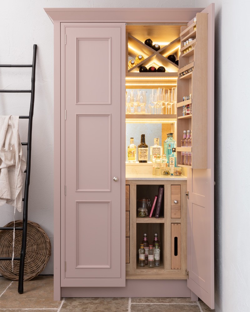 The soft-pink gin cabinet houses solid oak chopping boards, butler trays and bottle racks for all your storage needs. 📷 @1909_Kitchens & @paullmcraig #frederickgeorgekitchens #bespokekitchen #shakerkitchen #drinkscabinet #gin #pinkkitchen