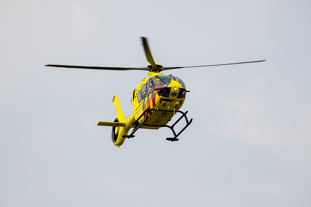 Traumahelicopter landt op kruising Soestdijksekade en Loosduinsekade, terwijl de auto's nog zo ongeveer onder de wieken doorrijden over het kruispunt.