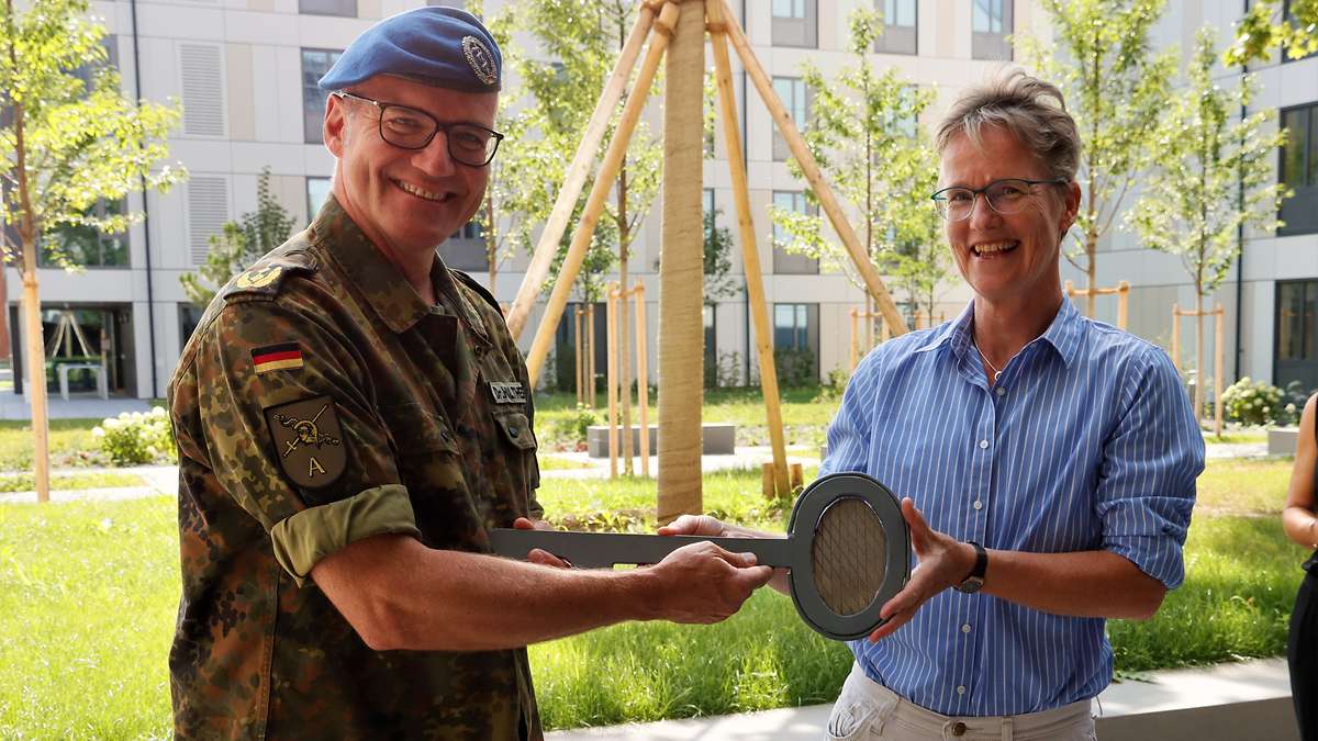 Eine Zivilistin übergibt einem Soldaten einen großen nachgemachten Schlüssel.