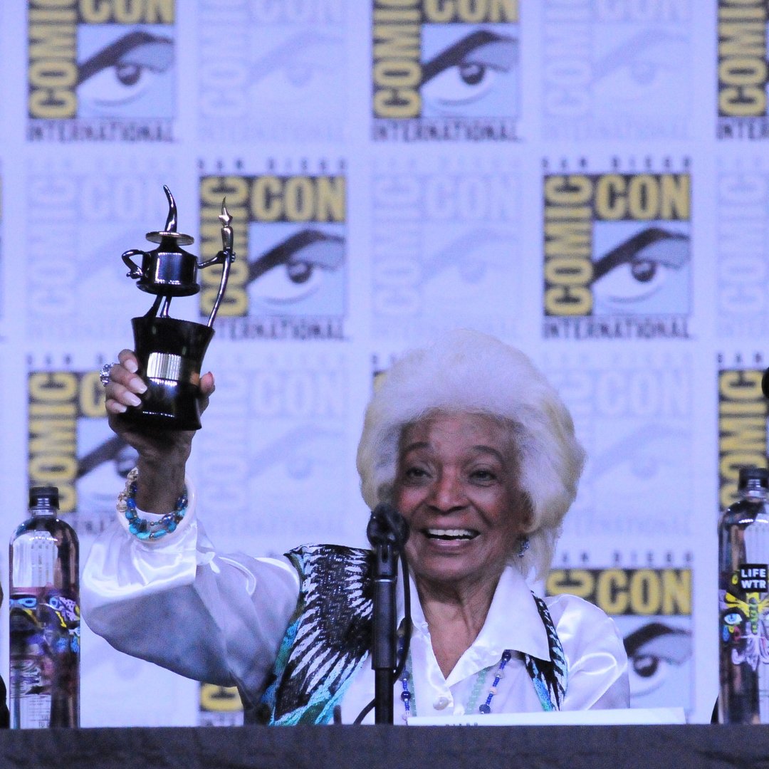 Comic_Con's tweet photo. We mourn the loss of Nichelle Nichols, trailblazing icon from Star Trek who portrayed Lt. Nyota Uhura. Advocating many causes including NASA, motivating women &amp; people of color to pursue careers in spaceflight. Our condolences to her family, friends,&amp; fans. 📷C.Gawlik © 2018 SDCC https://t.co/HCBHbUhkBJ