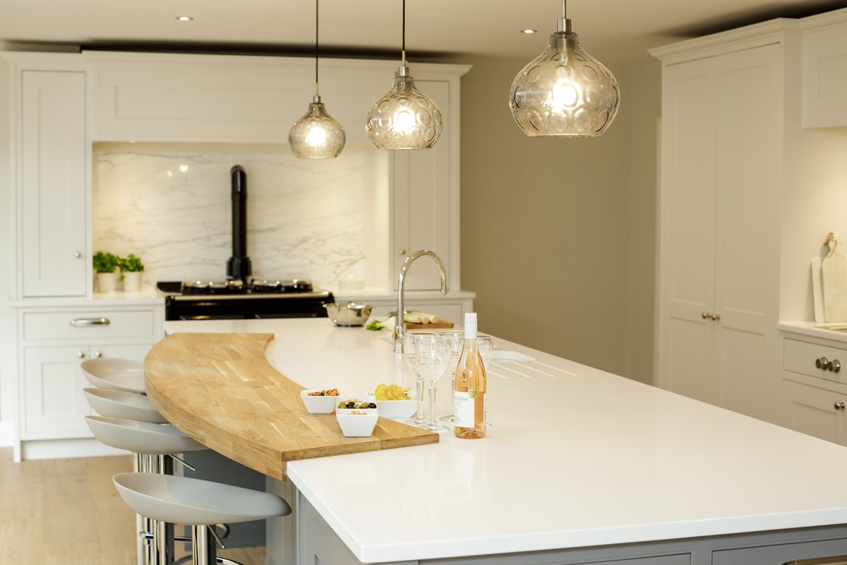 A little bit of flare…this beautifully crafted solid wood breakfast bar contrasting the cool stone island adds a touch of softness to this classic shaker kitchen. The round pendants and curved bar stools are the perfect finishing touches.