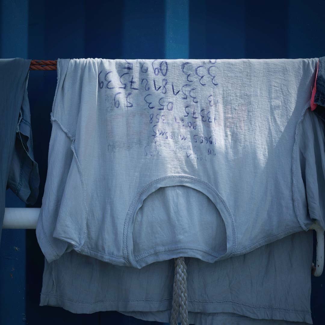 Ein Überlebender an Bord der  SEA-EYE 4 trug bei der Rettung ein T-Shirt, voll geschrieben mit Handynummern. Er hat alleine seine Heimat verlassen und die Flucht über das Mittelmeer gewagt. 
Seine größte Angst: Er könnte ertrinken und niemand würde seine Familie informieren. 1/2
