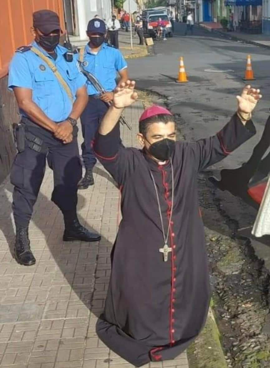 CelamWeb's tweet photo. Obispo de Matagalpa, Nicaragua - Mons. Rolando Álvarez de rodillas en la puerta de la Curia, ora rodeado por policías y antimotines que lo asedian y mantienen sitiado desde ayer. https://t.co/e397pvQNKL
