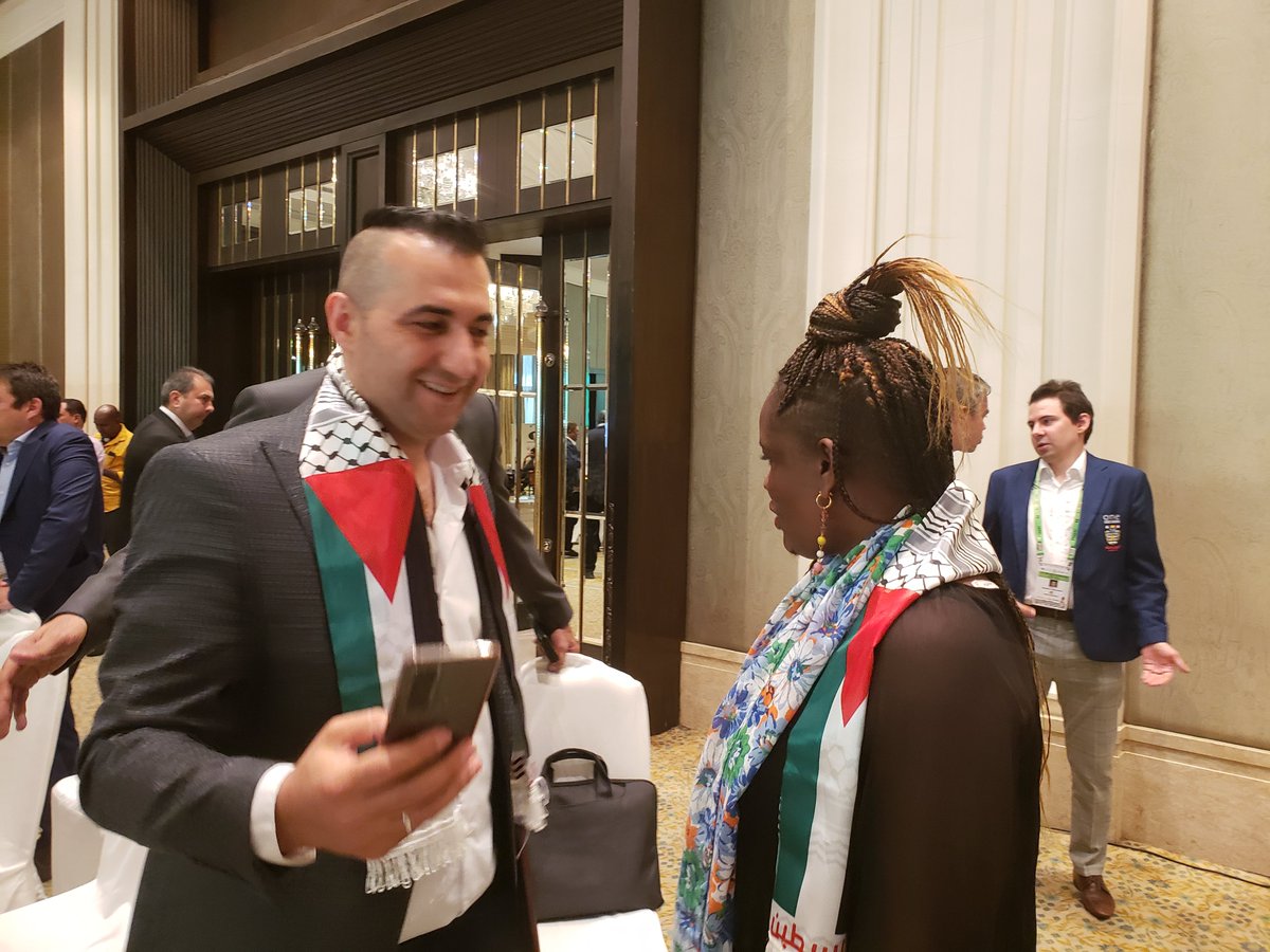 AnneMuyiwa's tweet photo. Many side events are going on especially in the #SayChess and #Uzbekistan booth. In a show of camaraderie, the Palestine team presented the new President of African Chess Confederation, Tshepito Lopang, with a sash... Other delegates from Africa discuss. @FIDE_chess @adeyemilekan https://t.co/CDAXuWAAI5