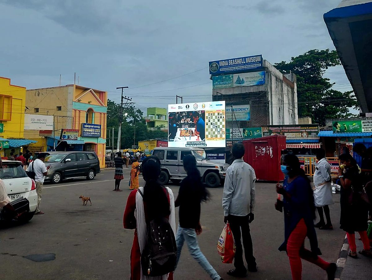 ninansusan's tweet image. A screen showing live chess games at the Mamallapuram bus stand. People stopping to catch a glimpse on a Sunday evening. A kid watches from a parked bus. What a  delightful sight! 

 #ChennaiChess2022 #olympiad2022