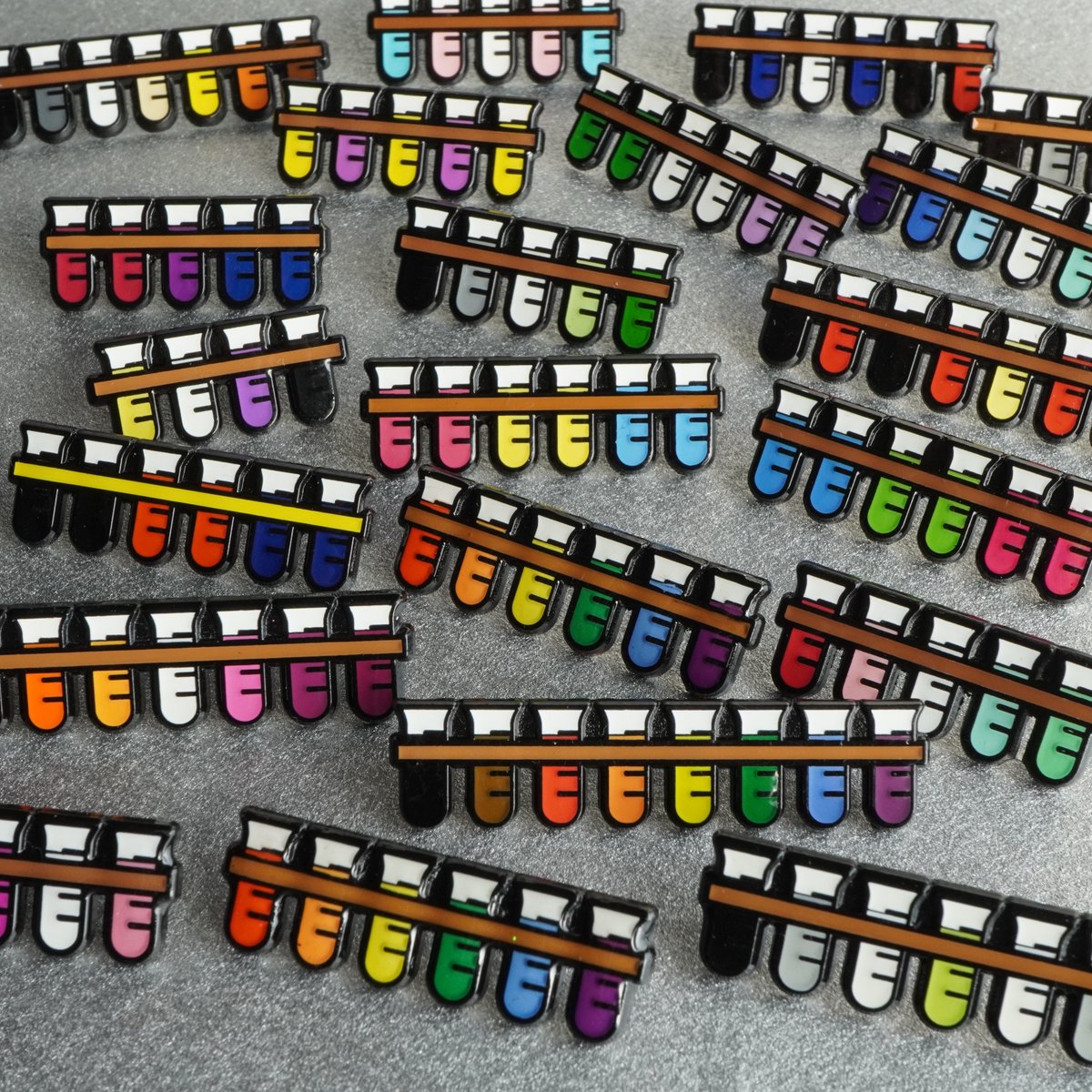 JamieBGall's tweet photo. They're here! 
I've been asked for lots of different identities to be reflected in my pins so I'd like to introduce the whole test tube family. Tell your pals &amp; let's brighten up some lab coats
🖤🤎❤️🧡💛💚💙💜
All profit goes to @aktcharity 
#LGBT #LGBTQ
https://t.co/tWuxfCIlbq https://t.co/iJKeM08g1R