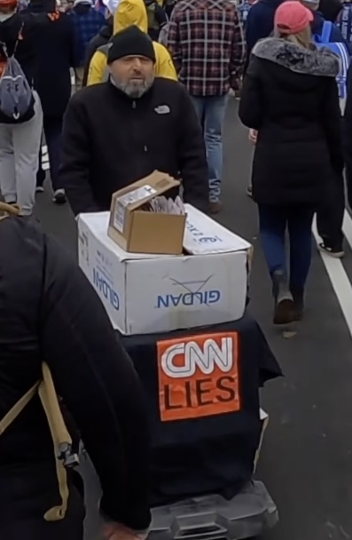 PacAntifa's tweet photo. On Jan 6th, 2021, this unidentified white supremacist who attended the 2017 Unite The Right rally was in DC. We think he was selling these "CNN Lies" shirts. The writing and/or barcodes on his merchandise boxes may be legible. See https://t.co/u6sYE2c9nh for video #IgniteTheRight https://t.co/FzWI87rnYa