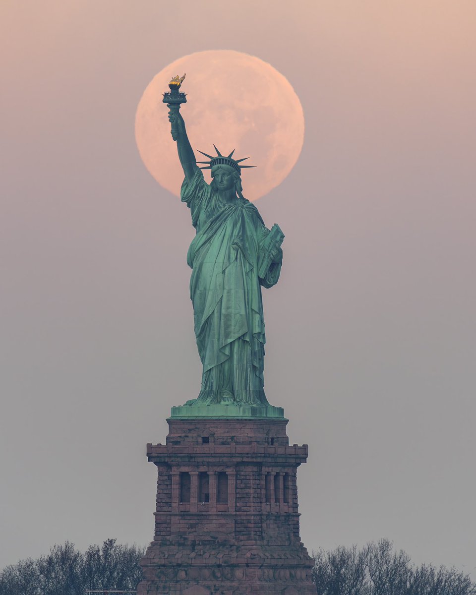 November’s Full Beaver Moon setting behind the Statue of Liberty whilst the Sun rises in New York City #NYC #LadyLiberty #fullMoon