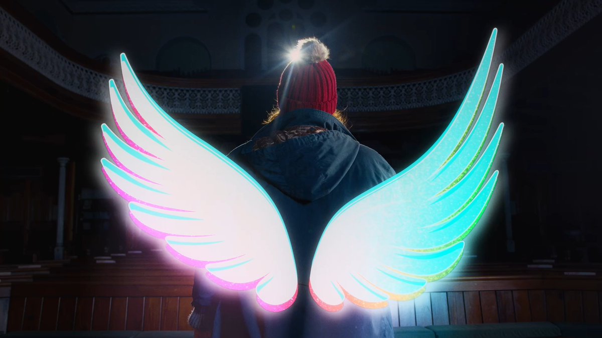 Lady stood with her back to us, revealing her wings have been brought back into reality. 