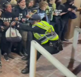 Those cops were some of the most pathetic I've ever seen. Embarrassing. Where does this cop think he's going to land if he falls backwards? Those are brick stairs behind him.