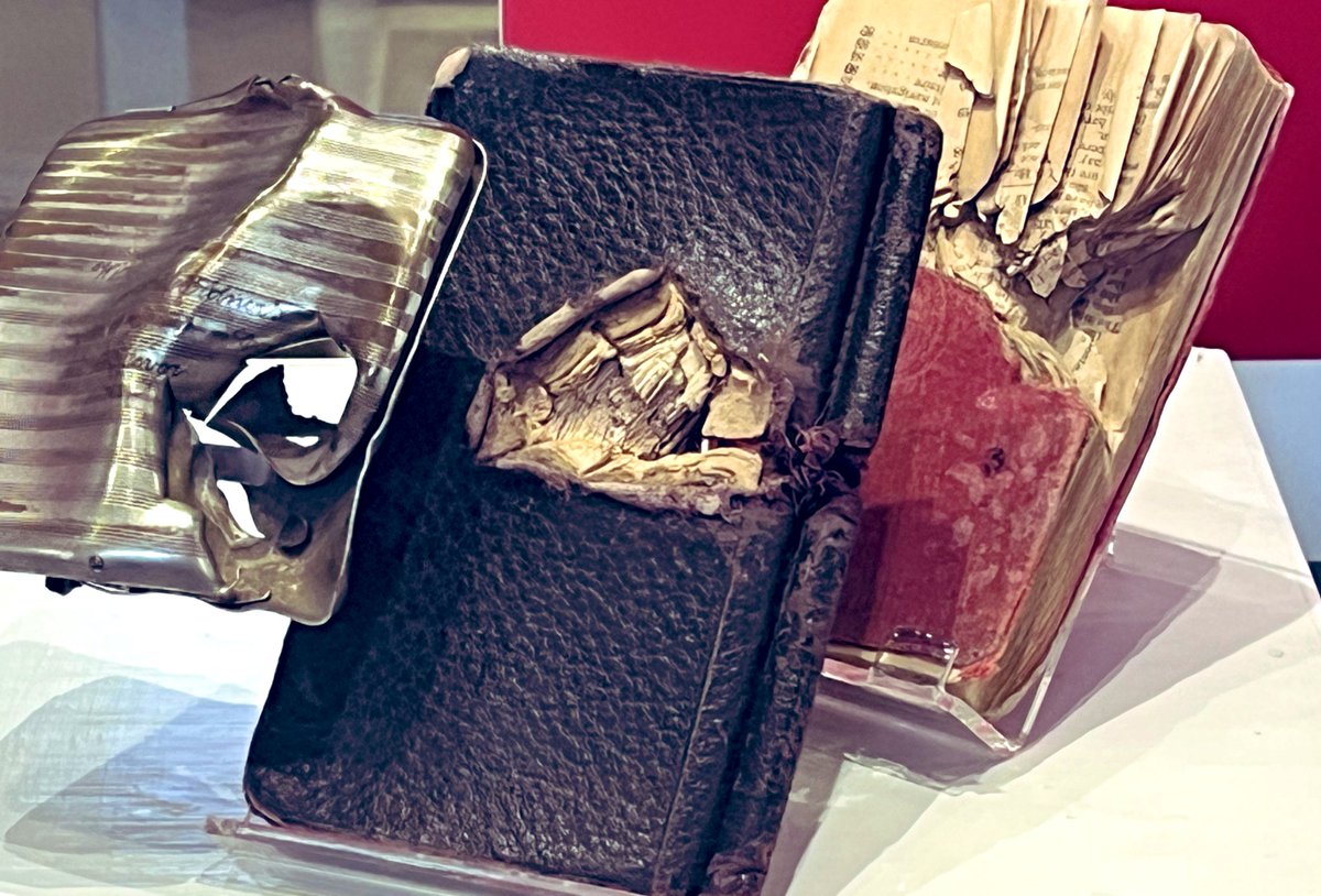 Cigarette case, note book and phrase book displayed to show how a bullet penetrated them in succession, with just a few pages of the phrase book finally stopping its track