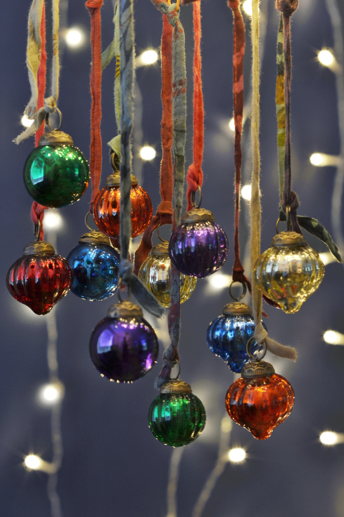 DecoratorsNotes's tweet image. This set of twelve glass baubles will bring a welcome pop of colour to your home this Christmas. Each set contains a vibrant mix of colours and shapes, all in a versatile miniature size. Finished with recycled sari ribbons and presented in a cotton bag. Made from recycled glass.