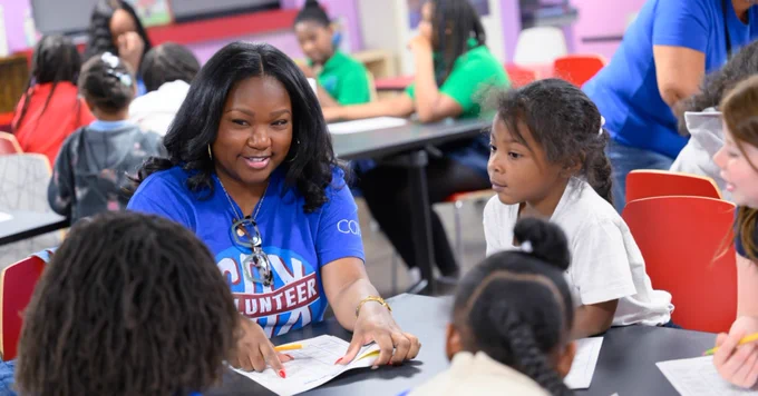 a cox volunteer doing a scavenger hunt at a table with young children