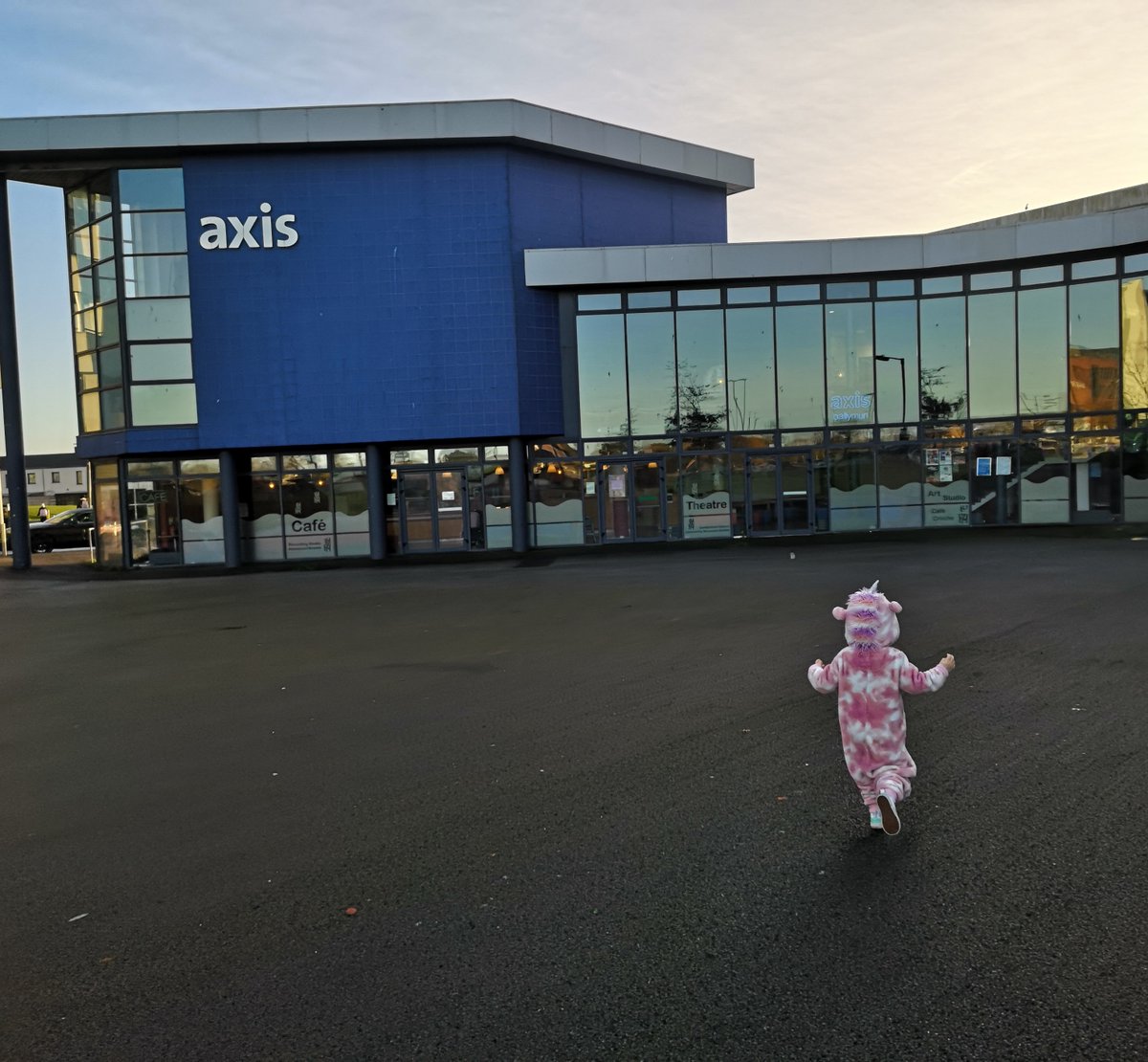 Unicorn alert! Spotted en route into Axis créche. We're having a PJ day as a fundraiser for @AsIAmIreland 🌈🦄 Image description : a small child wearing a fluffy unicorn onesie skips towards the Axis building.