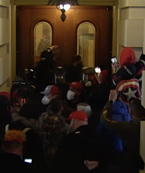 capitolresearc3's tweet photo. #SoloShield argues with the police for awhile, then he consults with this other guy in a covid mask and they both head out. Does anyone know who this is? (Red/gray hat in foreground left, next to #SoloShield also in a covid mask.) 8/ https://t.co/JtYVYgpkWt
