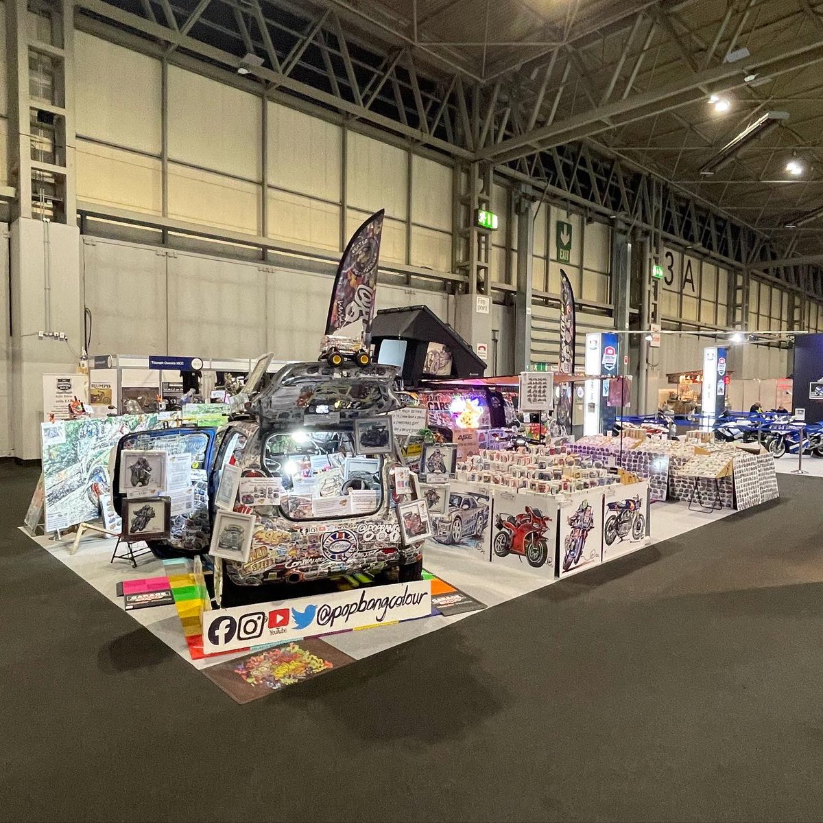 Popbangcolour's tweet photo. Day 2 of @motorcyclelive is go! Come say hi in hall 3 where you’ll find Mother Cook &amp; I 

The @asecustommc is lit up by the POPBANGCOLOUR missionneonsigns with the Latitude Tents on top of the van. 

The @GarageStyleLtd flooring adding some colour to the stand too #MotorcycleLive https://t.co/BH3D6hKMxu
