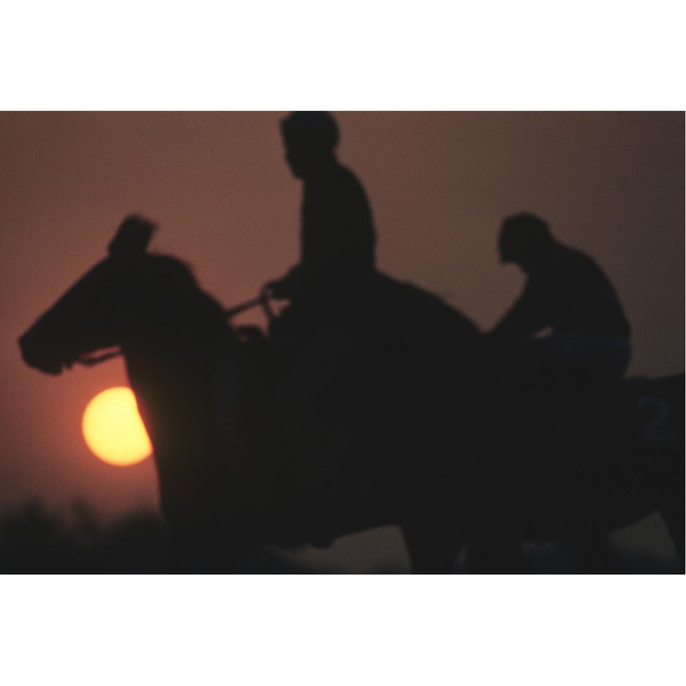 A silhouette view of jockeys on horses at sunset before the 9th race at Santa Anita Park. Arcadia, California. January 27, 1965. #NeilLeifer #Photography #Sunset #Jockeys #Horses