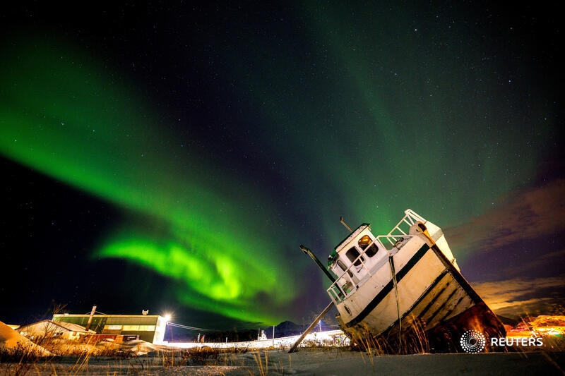 The Northern Lights, or Aurora Borealis, illuminate the night sky over a boat on the shore in Sommaroy, Norway. More photos: reut.rs/46oD82t 📷 @LisiNiesner