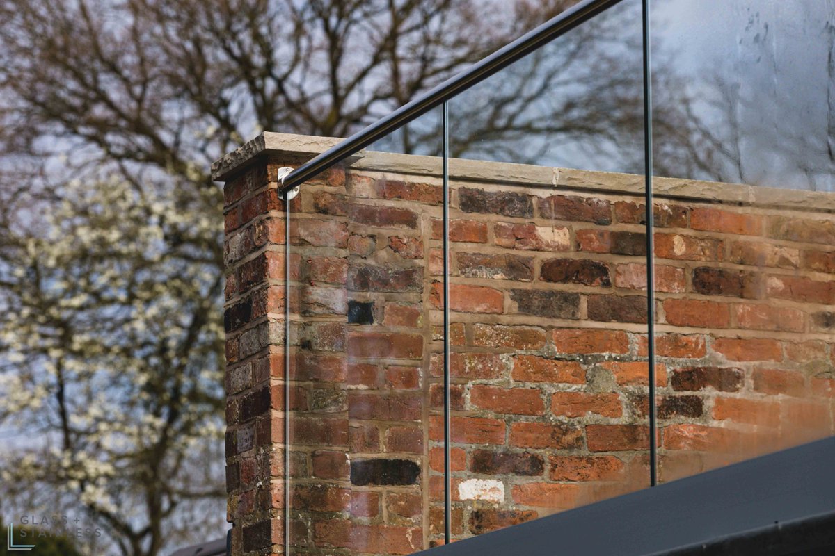 A stunning juxtaposition of traditional and contemporary architecture: a brick wall meeting a glass and steel balustrade, creating a modern piece of beauty and elegance.