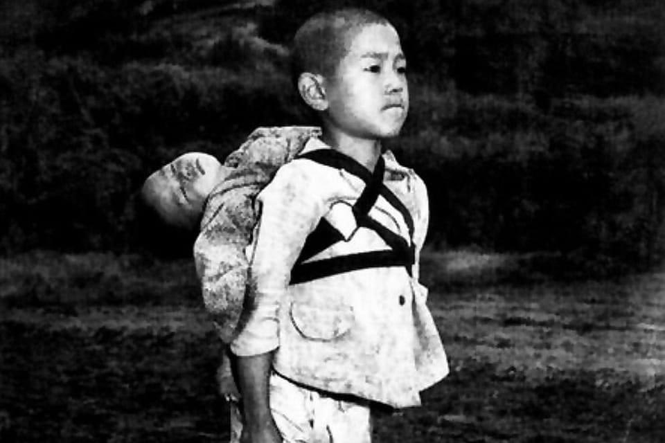 MarkitoShango's tweet photo. El fotógrafo, Joe O'Donnell, le dijo esto a un entrevistador japonés: “Vi pasar a un niño de unos diez años. Llevaba un bebé a la espalda. En esos días en Japón, a menudo veíamos niños jugando con sus hermanos o hermanas pequeños sobre sus espaldas, pero este niño era claramente diferente. Pude ver que había venido a este lugar por una razón seria. No llevaba zapatos. Su rostro era duro. La cabecita estaba inclinada hacia atrás como si el bebé estuviera profundamente dormido. El niño se quedó allí durante cinco o diez minutos.

Los hombres con máscaras blancas se acercaron a él y en silencio comenzaron a quitar la cuerda que sujetaba al bebé. Fue entonces cuando vi que el bebé ya estaba muerto. Los hombres sujetaron el cuerpo por las manos y los pies y lo colocaron sobre el fuego. El chico se qued�� allí erguido, sin moverse, mirando las llamas. Se mordía el labio inferior con tanta fuerza que brillaba con sangre. La llama ardió como el sol poniéndose down. El niño se dio la vuelta y se alejó en silencio.”

Esta foto inspiró la muy aclamada película La tumba de las luciérnagas, una película de anime que se considera una de las mejores películas de guerra de todos los tiempos en todos los géneros.